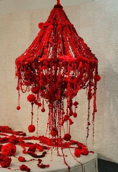 a red chandelier hanging from the ceiling in front of a white wall with blood dripping all over it