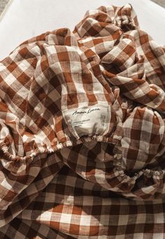 an unbuttoned brown and white checkered shirt laying on top of a piece of paper