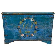 an old blue painted chest with flowers and leaves on the front, decorated with monograms