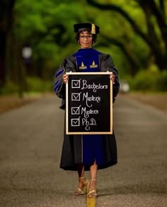 a woman in graduation gown holding a blackboard with the words bachelors written on it