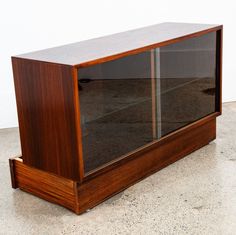 a large wooden cabinet with glass doors on the top and bottom shelf is shown in front of a white wall