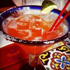 a close up of a drink in a glass with ice and straws on the rim