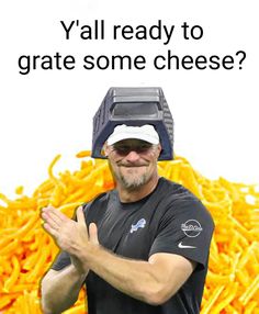 a man wearing a hat and glasses standing in front of a pile of cheese