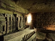 the light shines brightly in an old stone tunnel with carved pillars and carvings on the walls