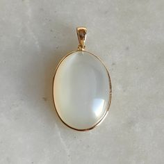 ITEM DESCRIPTION: >> The pendant is made from Solid 14K Yellow Gold. Gemstone used is absolutely natural and ethically sourced.  >> Natural White Moonstone in Cabochon pear shape with bezel setting is studded on it with utmost precision.  >> This is a minimalist design and is absolutely hassle-free and everyday jewelry.  Gem: White Moonstone Gem size: 17x24 mm  Gem weight: 23.35 carats Gold purity: 14K (58.33% approx.) Gold weight: 0.69 grams  Gross weight: 5.36 grams The Gold purity is guarante Elegant Yellow Gold Moonstone Ring With Large Stone, Gold Polished Moonstone Jewelry, Gold Moonstone Jewelry With Polished Finish, Elegant Gold Moonstone Ring With Natural Stones, Elegant Gold Moonstone Ring With Large Stone, Elegant Moonstone Oval Pendant Jewelry, White Moonstone Oval Cabochon Ring In 14k Gold, Elegant Oval Moonstone Chalcedony Ring, White Oval Cabochon Moonstone Ring In 14k Gold