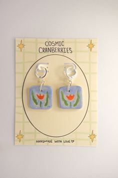 a pair of earrings on a card with the words cosmic cranberries hanging from it