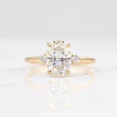 a yellow gold engagement ring with an oval cut diamond in the center and side stones