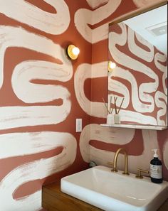 a bathroom sink sitting under a mirror in front of a wall painted with white paint