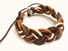 a close up of a bracelet on a white surface with brown and tan braiding