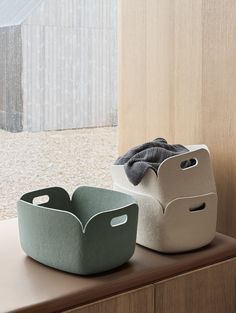 two storage baskets sitting on top of a wooden shelf next to a window sill