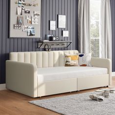 a living room with blue walls and white couches in front of a window on top of a wooden floor