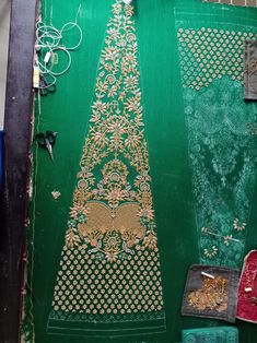 an intricately designed piece of cloth is displayed on a green surface with other items