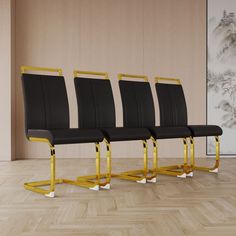 four black leather chairs with gold metal legs in front of a wall and wood floor