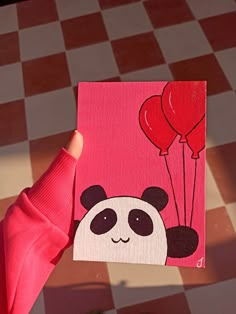 a person holding up a card with a panda bear on it and balloons in the air