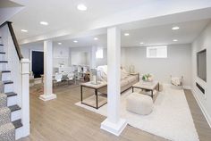 a living room filled with furniture next to a stair case in front of a tv