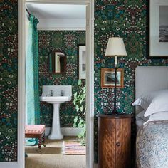 a bedroom with green wallpaper and a white pedestal sink in the corner next to a bed