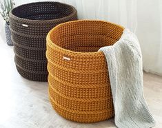 three crocheted baskets sitting next to each other on the floor in front of a window