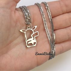 a person is holding two different necklaces in their hand and one has a cow on it