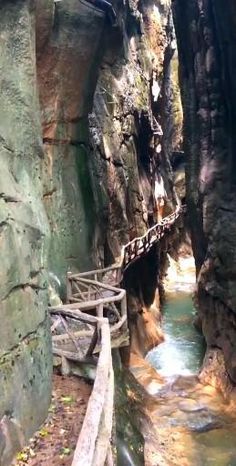 a wooden bridge over a small stream in a canyon