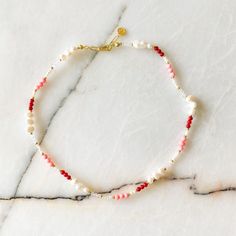 a red and white beaded bracelet on marble