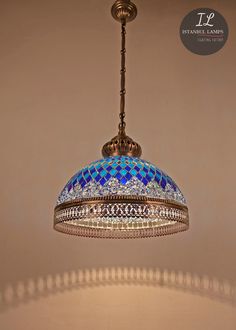 a chandelier hanging from the ceiling with blue and white mosaic tiles on it