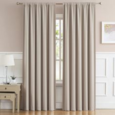 a living room with beige curtains and wooden floors