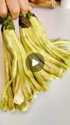 a person is cutting up bananas on a white table with other people in the background