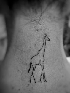 a small giraffe tattoo on the back of a man's upper neck