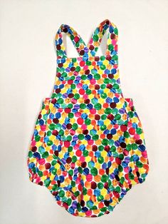 a child's swimsuit with multicolored circles on it, hanging from the wall