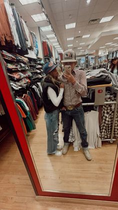 a man and woman standing in front of a mirror taking a selfie with their cell phone