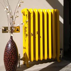 a yellow radiator next to a vase with flowers in it