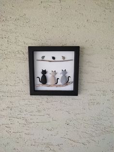 three black and white cats are sitting on a branch in a shadow box with birds perched on it