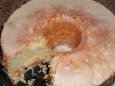 a frosted donut sitting on top of a counter next to a piece of cake