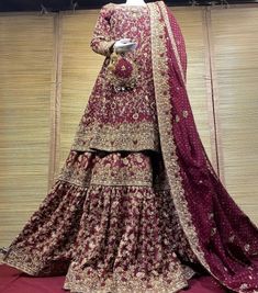 a mannequin dressed in a maroon and gold lehenga with matching dupatta