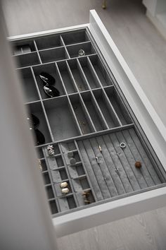 an open drawer with several pairs of shoes and jewelry in it on top of a wooden floor