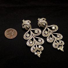 *Description: This is a great pair of mid-century chandelier drop rhinestone earrings with clear rhinestones at a length of 2 1/2 Inches from the 1960s. This pair of earrings would look great at a wedding or any formal occasion. The backs have the comfort clips which have a patent number on the backs. All stones are in place and they are full of shine and sparkle. The backing is a smooth silver rhodium plated backing. This would be a great addition to your vintage jewelry collection or make a gr Vintage Silver Chandelier Earrings For Formal Occasions, Silver Vintage Chandelier Earrings For Formal Occasions, Vintage Silver Bridal Earrings For Evening, Vintage Diamond Clip-on Earrings, Vintage Diamond Drop Earrings, Vintage Rhinestone Drop Earrings, Vintage Silver-colored Diamond Earrings, Vintage Earrings With Diamond Accents For Evening, Vintage Evening Earrings With Diamond Accents