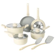 an assortment of white pots and pans with utensils next to each other