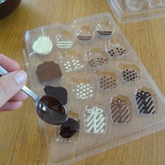 a person holding a spoon with some chocolates in it on top of a table