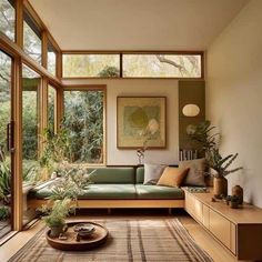 a living room filled with lots of furniture and plants on top of a wooden floor