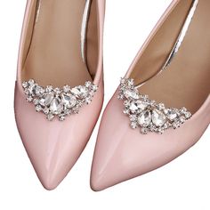 a pair of pink high heeled shoes with crystal decorations on the toe and heels