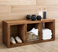 a wooden shelf with three cubbys and some towels on the floor next to it