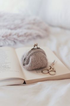 an open book with a knitted purse sitting on top of it