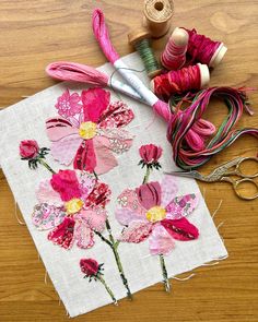 a table topped with pink flowers and spools of thread