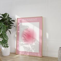 a pink poster with the words alignmentment on it next to a potted plant