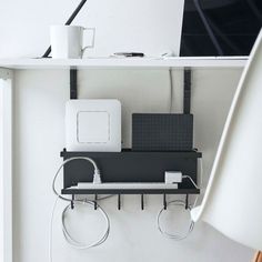 a computer desk with two computers and wires on the shelf next to it, along with a lamp