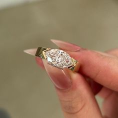 a woman's hand holding a ring with a large diamond in the middle,