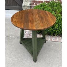 a wooden table sitting on top of a sidewalk next to a planter and brick wall