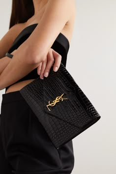 SAINT LAURENT's clutch has been made in Italy from glossy croc-effect leather in a slim, envelope shape and has enough space for your phone, cards and keys. Topped with the brand's iconic 'YSL' plaque, it comes with a detachable wristlet strap to free up your hands. Clutch Designer Luxury, Ysl Croc Bag, Ysl Clutch Bag, Clutch Purse Outfit, Ysl Clutch Outfit, Ysl Envelope Clutch, Ysl Wristlet, Purse List, Saint Laurent Pouch