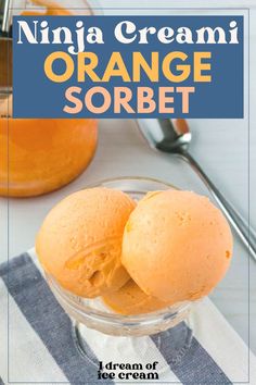 two scoops of orange sorbet in a glass bowl on a striped towel