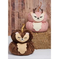 two stuffed animals sitting next to each other on top of hay bales in front of wooden planks